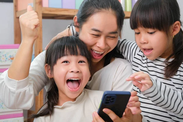 Anne ve kız oynuyor, sarılıyor, akıllı telefonlarda selfie çekiyor, çizgi film izliyor ya da evde online oyunlar oynuyor. Mutlu aile ve Anneler Günü konsepti.