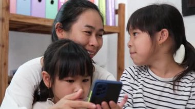 Anne ve kız oynuyor, sarılıyor, akıllı telefonlarda selfie çekiyor, çizgi film izliyor ya da evde online oyunlar oynuyor. Mutlu aile ve Anneler Günü konsepti.