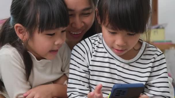 母亲和女儿在玩和拥抱 在智能手机上自作主张 在家里看卡通片或玩网络游戏 快乐关爱家庭和母亲节的概念 — 图库视频影像