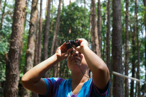 年轻女人用双筒望远镜看森林里的鸟儿 带着工具观察森林自然的女游客 健康的生活方式和生态旅游 — 图库照片