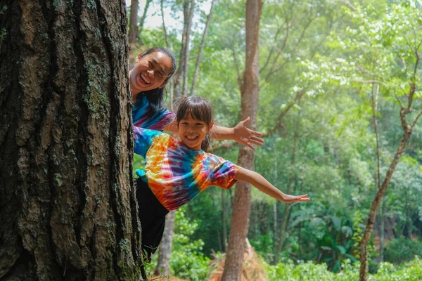 快乐的家人躲在树后 在公园里玩耍 快乐的母亲和女儿躲在树干后面绿色环保生活方式 爱与保护自然的概念 — 图库照片