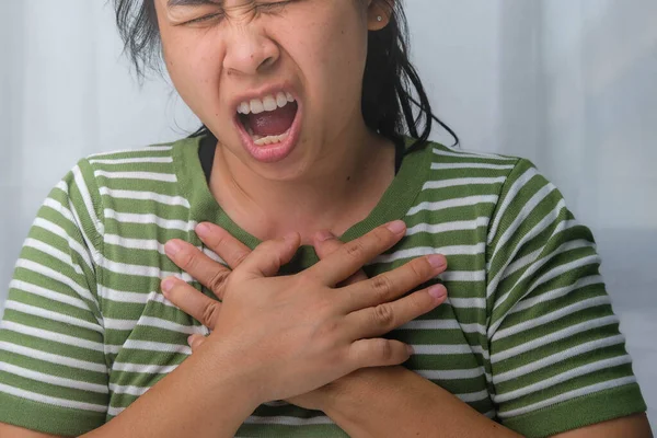Woman holding her chest with a heart attack. Women have chest pain caused by heart disease, heart attack, heart leak, coronary artery disease, acute pain can cause a heart attack.