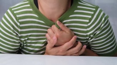 Göğsünü acı ifadesiyle tutan bir kadın. Kadınların göğüs ağrısı kalp krizi, kalp sızıntısı ya da koroner arter hastalığından kaynaklanır..