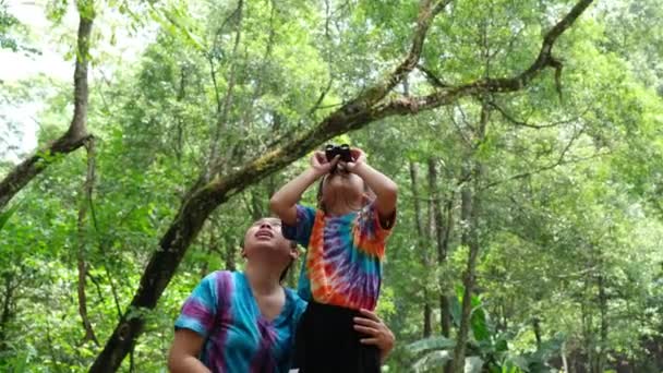 一緒に休暇で双眼鏡を見ながら活動をしている母親と娘 双眼鏡を使って勉強している母親と2人の娘 自然歩道で休暇中の自然を学ぶ — ストック動画