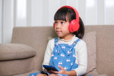 Sabah evde uyandıktan sonra elinde bir fincan kahveyle kanepede kitap okuyan mutlu genç bir kadın. Yaşam tarzı, boş zaman ve rahatlama.