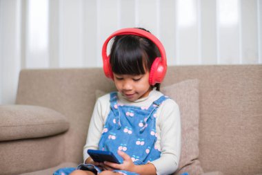 Sabah evde uyandıktan sonra elinde bir fincan kahveyle kanepede kitap okuyan mutlu genç bir kadın. Yaşam tarzı, boş zaman ve rahatlama.