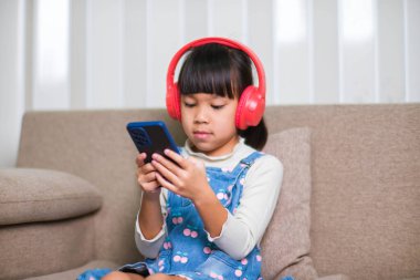 Sabah evde uyandıktan sonra elinde bir fincan kahveyle kanepede kitap okuyan mutlu genç bir kadın. Yaşam tarzı, boş zaman ve rahatlama.