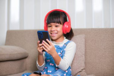 Sabah evde uyandıktan sonra elinde bir fincan kahveyle kanepede kitap okuyan mutlu genç bir kadın. Yaşam tarzı, boş zaman ve rahatlama.