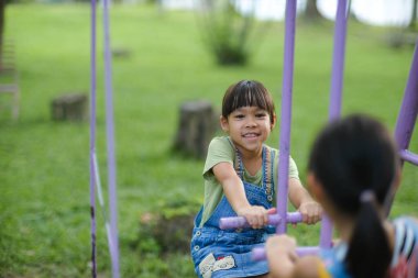 İki tatlı kız kardeş yaz boyunca oyun alanında oynarken eğleniyorlar. Sevimli küçük bir kız, gülücükler saçarak bir parkta at sallıyor. Çocuklar için aktif yaz tatili.