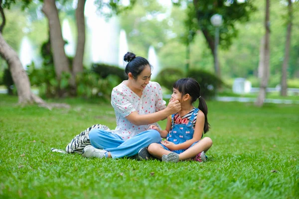 妈妈和小女儿一起坐在公园的草地上 妈妈和她的小女儿在绿色的自然公园里玩得很开心 快乐的家庭观念 母亲节 — 图库照片