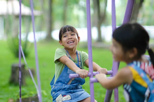 stock image Two cute little sisters having fun playing in the playground during summer. Adorable little girl rocking a horse in a playground with a smile and laughter. Active summer leisure for kids.