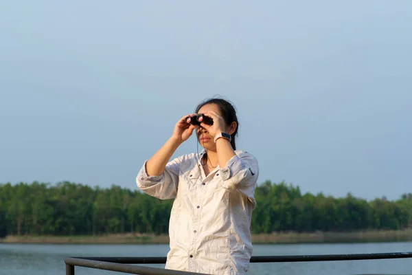 年轻的女探险家 带着双筒望远镜探索自然或在户外观鸟 年轻的女人通过双筒望远镜看水库里的鸟儿 — 图库照片