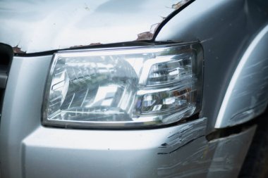 Araba tamponu çatlamış ve boyasında derin çizikler var. Küçük bir kaza yüzünden arabanın ön tamponunda çizikler var..