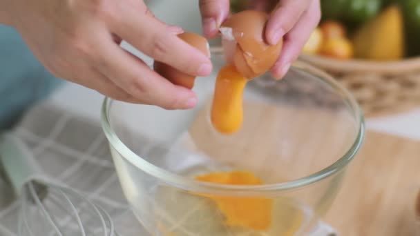 明るいキッチンで若い女性の料理は 手がボウルに滴下新鮮な卵の黄身を割れた 健康的な料理のための材料を準備します 自家製食品 — ストック動画