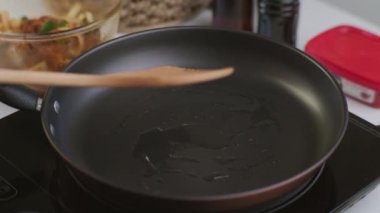 Mutfaktaki tavada kepçeyle kızartılmış kimchi ve kurobuta domuz eti tutan eller. Öğle yemeği için Kore ev yemeği.