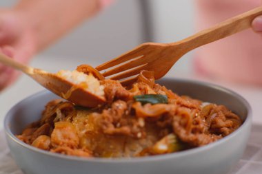 Kore yemeği - Kaşık tutan eller kızarmış kimchi ve klozette pilav ile Kurobuta domuz eti yiyor. Öğle yemeği için Kore ev yemeği.