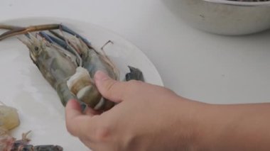 Mutfakta karides soyan kadın eller. Eldeki karides pişirmeye hazırlanıyor..