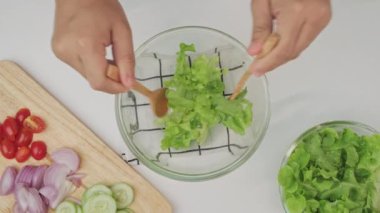 Mutfakta taze organik sebze salatası yapan bir kadın. Kadın elleri evde lezzetli sağlıklı yiyecekler hazırlıyor, bir kasede sebzeleri karıştırıyor, yakın plan.