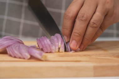 Kesme tahtasında taze kırmızı soğan dilimlemek için bıçak kullanan kadın, yakın plan. Şef tahta kesme tahtasındaki keskin bir bıçakla arpacık soğanlarını doğradı. Ev yemeği hazırlıyorum.