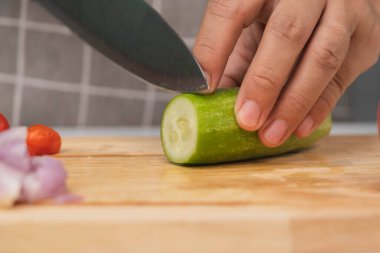 Kesme tahtasındaki salatalıkları kesmek için bıçak kullanan bir kadın. Yakın plan. Mutfak bıçaklı kadın evde salatalık kesiyor. Ev yemeği hazırlıyorum.