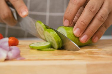 Kesme tahtasındaki salatalıkları kesmek için bıçak kullanan bir kadın. Yakın plan. Mutfak bıçaklı kadın evde salatalık kesiyor. Ev yemeği hazırlıyorum.