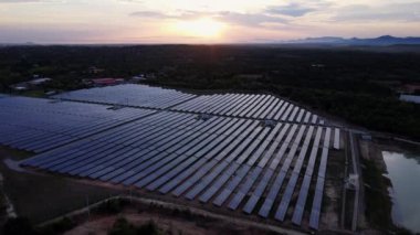 Günbatımı gökyüzü arka planında güneş panelleri, yeşil temiz Alternatif enerji kavramı. Gün batımı ışınları fotovoltaik enerji santralinin üzerinde.