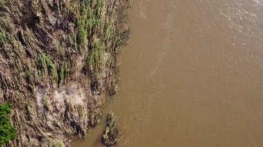 Kuzey Tayland 'da yağmur mevsiminde bir nehirde akan turbikli kahverengi orman suyunun havadan görünüşü. Chiang Mai köyleri ve Ping nehri insansız hava aracından görünüyor..