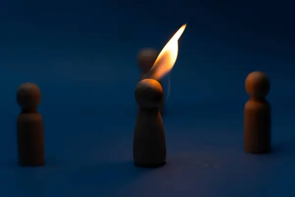 Tahta figür, kalabalıktan bir ateşle izole edilmiş, kafa karışıklığı ve başkalarıyla çatışma nedeniyle kovulmuş. Muhalefet, reddedilme, şüphe, öfke ve intikam kavramları.