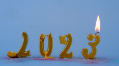 Yeni yıl arkaplanı 2023 yılının altın ışıklı mumlarıyla mutlu yıllar. 2023 yılının sayıları. Mavi arka planda yanan altın mumlar tarafından yapıldı.. 