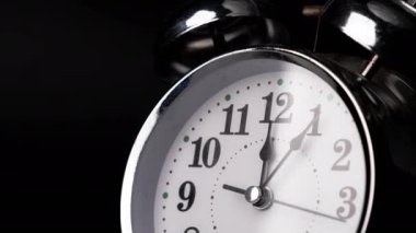 Siyah arkaplanda geçmişe dönük alarmlı saatin yakın plan görüntüsü. Retro çalar saat ileri gidiyor. Saat ileri gidiyor, saatin başlangıcı 12: 00 ya da 12: 00..