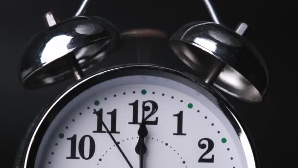 古い目覚まし時計は午前12時か午後12時でした ブラックバックのタイムラウンドでレトロなアラーム時計のクローズアップ 時計の手が速く動く — ストック動画