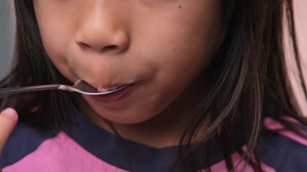 一个可爱的小女孩用勺子吃巧克力冰淇淋的特写镜头 小女孩在咖啡馆里用纸杯里的勺子吃着番茄酱 漂亮的孩子喜欢冷甜点 — 图库视频影像