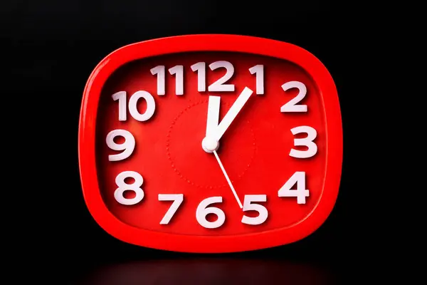Close-up of red clock time lapse on black background. A red wall clock running fast.