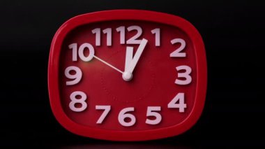 Siyah arkaplandaki kırmızı saatin zaman aşımına yakın çekim. Kırmızı duvar saatinin elleri hızlı hareket ediyor..