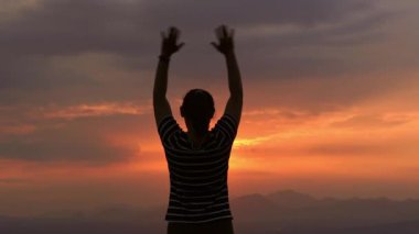 Açık havada yaz günbatımında dinlenen genç bir kadının silueti. Ufukta umut vaat eden hayalperest genç bir kadın..