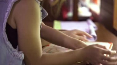 İki tatlı kız öğrenci kütüphanede birlikte eğitim oyunları oynuyorlar. Arkadaşlarıyla oyun oynayan bir kız..