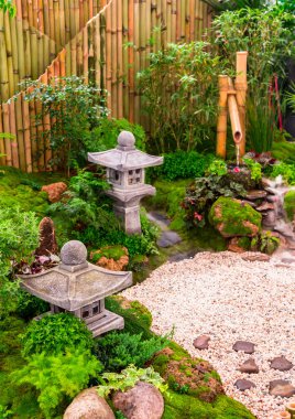 Minimal Japanese garden in home with small stone lantern and bamboo fountain and moss and flowers. clipart