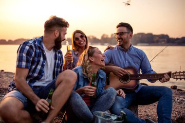 Bir grup arkadaş kumsalda eğleniyor, bira içiyor..