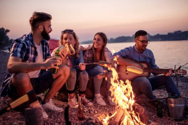 Arkadaşlar ateşin etrafında piknik yapıyor. Bir grup genç arkadaş gece piknik yapıyor.. 