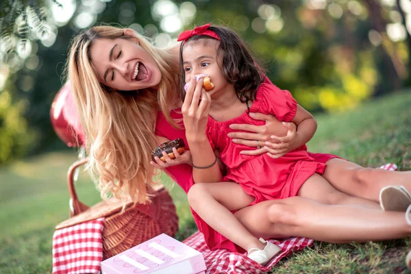 母と小さな娘が公園でドーナツを食べ 楽しんで — ストック写真