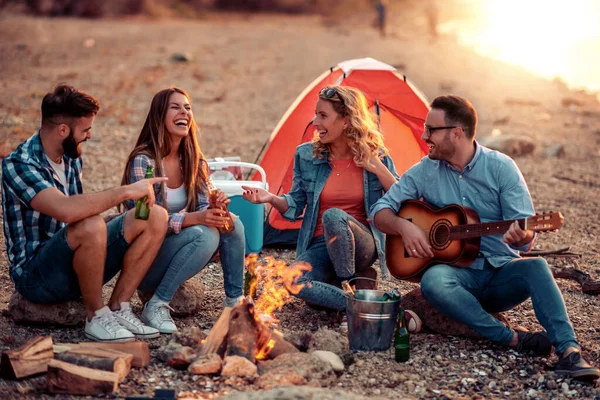 stock image Happy friends playing guitar and enjoying on the beach.