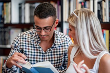 Uluslararası öğrencilerden çiftler kütüphanede okuyorlar. Eğitim, insanlar, üniversite ve yaşam tarzı kavramı.