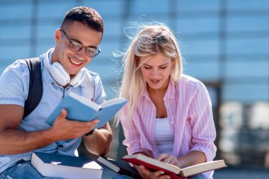 Açık havada kitap okuyan bir çiftin portresi, bankta oturup kitap okuyorlar..