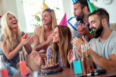 Celebration,friends, party and birthday concept - smiling women blows candles on her birthday cake.