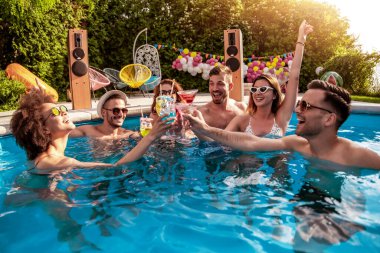 Group of friends having party in pool, drinking cocktails and enjoying together. clipart