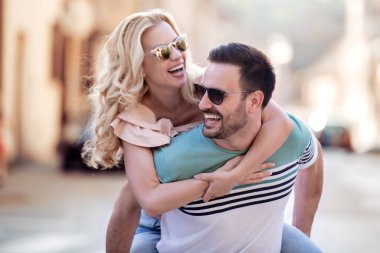 Dışarıda birbirine aşık gülümseyen bir çift. Sokakta sarılan mutlu genç bir çift..