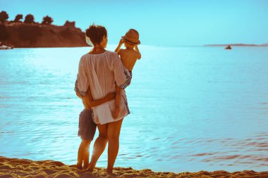 Mother with two kids playing on the beach, enjoying on summer vacation.