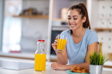 Beautiful woman drinking her orange juice at home.            