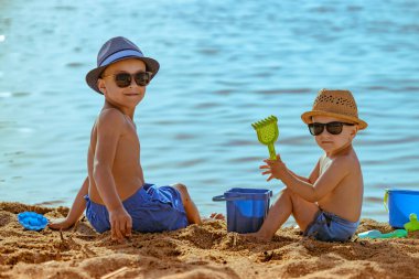 Little boys playing on the beach with toys. Family vacation.