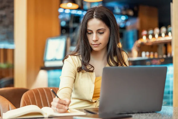 Young woman at the bar using laptop.Female working on laptop in modern cafe.